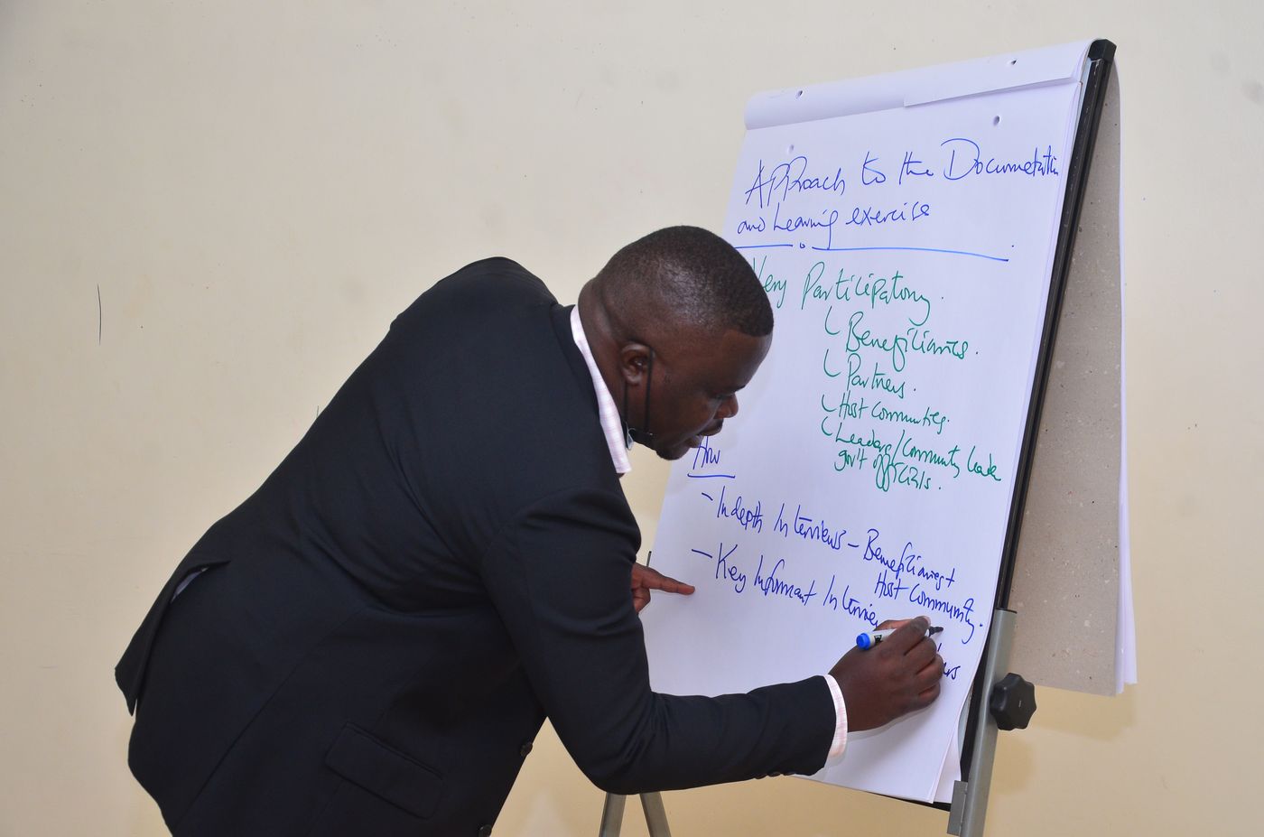 A facilitator writing a participatory documentation and learning approach on a flip chart during a workshop