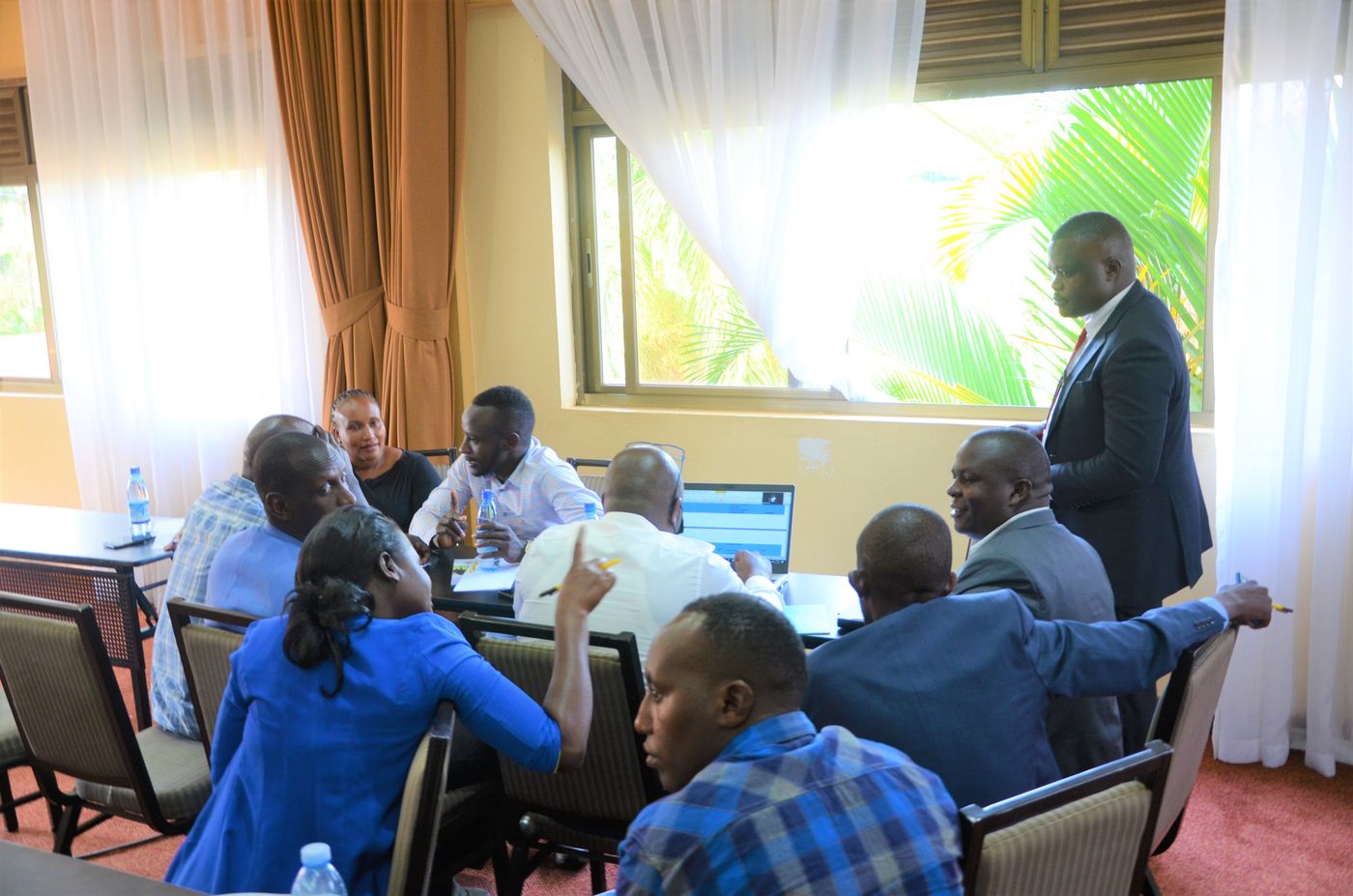 Stakeholders working in small groups around a table with a laptop during a validation workshop